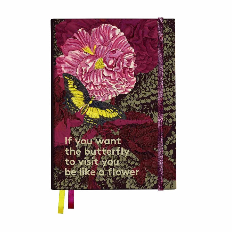 A hardcover notebook with a dark burgundy and green floral patterned cover, featuring a large pink flower, a yellow and black butterfly, and the quote 'If you want the butterfly to visit you be like a flower' in cream text. A pink elastic closure band is visible on the right, with yellow and pink ribbon bookmarks hanging from the bottom.