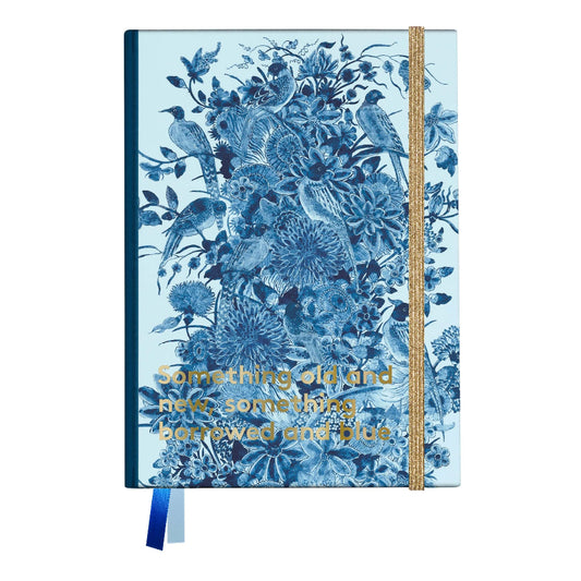 A hardcover notebook with a light blue cover decorated with a detailed blue floral and bird toile pattern, featuring gold foil text that reads 'Something old and new, something borrowed and blue'. It has a gold elastic closure band and a blue ribbon bookmark.