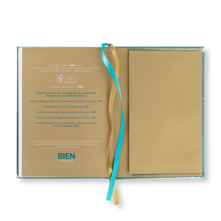 An open hardcover book or album with tan pages, a matching tan pocket page, and two hanging ribbons in turquoise and gold, photographed on a white background. The left page shows printed text and the BIEN MUSIQUE logo.