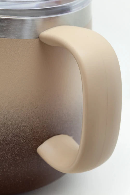 Close-up of a beige insulated mug handle and upper body, showing a frosted gradient from beige at the top to dark brown at the bottom, with a stainless steel rim and clear lid visible.