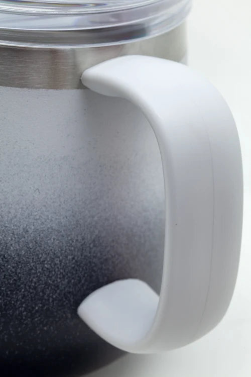 Close-up of a handled insulated tumbler with a white handle and a dark-to-silver gradient body, shown against a light neutral background.