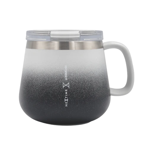 A Next Time LesMKore insulated travel mug with a handle, featuring a black-to-white gradient design and a clear lid, shown on a white background.