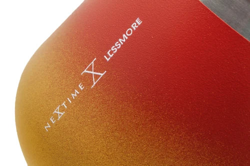 Close-up of a red and gold gradient dome-shaped product with white printed text reading 'NEXTTIME X LESSMORE' on a white background.