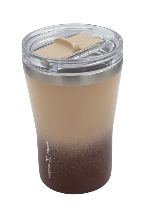 A travel tumbler with a clear lid and a beige-to-dark-brown gradient design, featuring the text 'NEXT THE COMFORT' printed vertically on the side.
