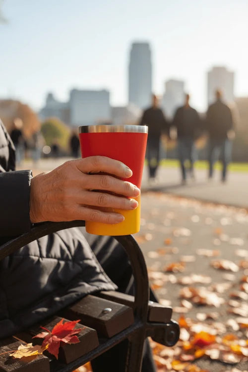 Person holding a red and yellow cup with a cityscape in the background