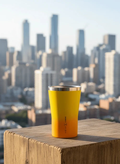 Yellow cup on a wooden ledge with a city skyline in the background