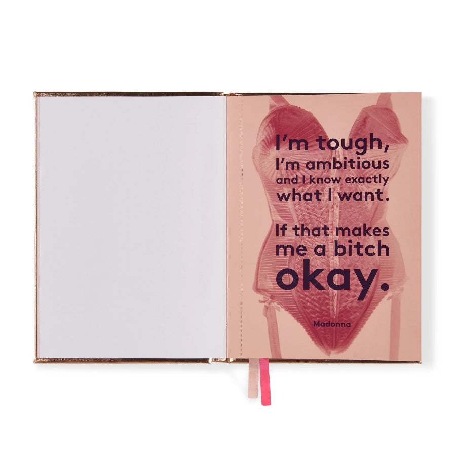 An open notebook or journal with a rose gold metallic edge, featuring a pink cover page with a graphic of a corset and a quote attributed to Madonna, shown on a white background.