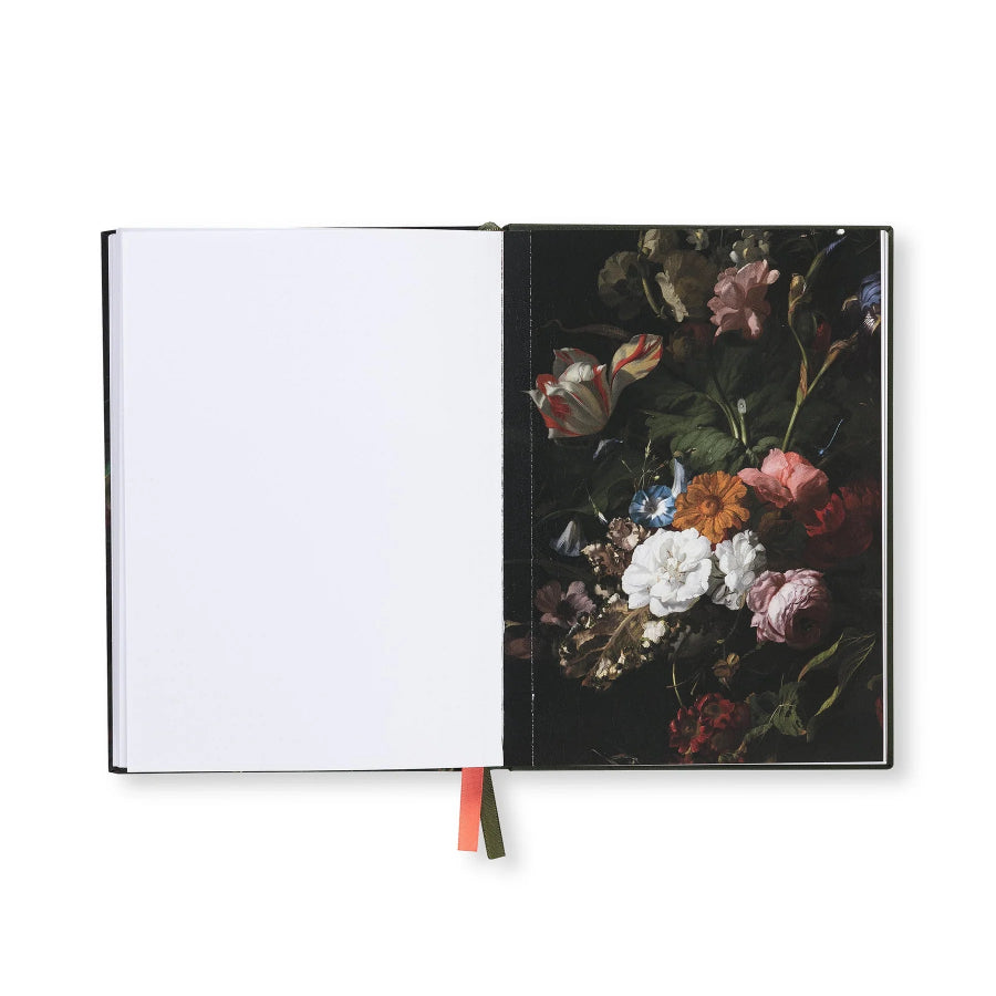An open notebook or journal on a white background, showing a blank white left page and a right page with a dark floral painting featuring pink, white, and orange flowers with green leaves.
