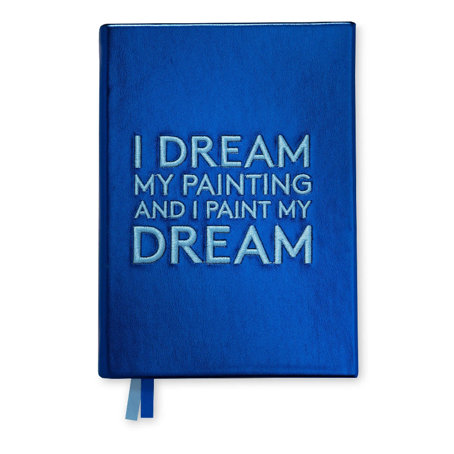 A blue hardcover notebook with the phrase 'I DREAM MY PAINTING AND I PAINT MY DREAM' embossed on the front cover, featuring a blue ribbon bookmark at the bottom, set against a plain white background.