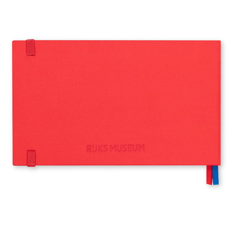 A red hardcover notebook with an embossed 'RUKS MUSEUM' logo on the front cover, featuring two red elastic closure tabs on the left and a red and blue ribbon bookmark on the right, set against a plain white background.
