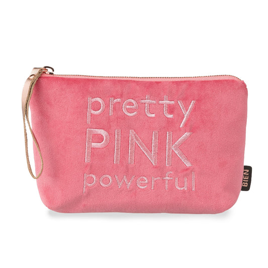 A pink velvet cosmetic pouch with the words 'pretty PINK powerful' embroidered on the front. It features a wristlet strap on the left side and a small black brand tag on the right side, set against a plain white background.