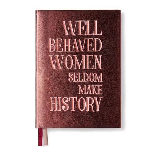 A hardcover notebook with a textured dark reddish-brown cover and rose gold embossed text that reads 'WELL BEHAVED WOMEN SELDOM MAKE HISTORY'. A thin red and white ribbon bookmark is visible at the bottom left, set against a plain white background.