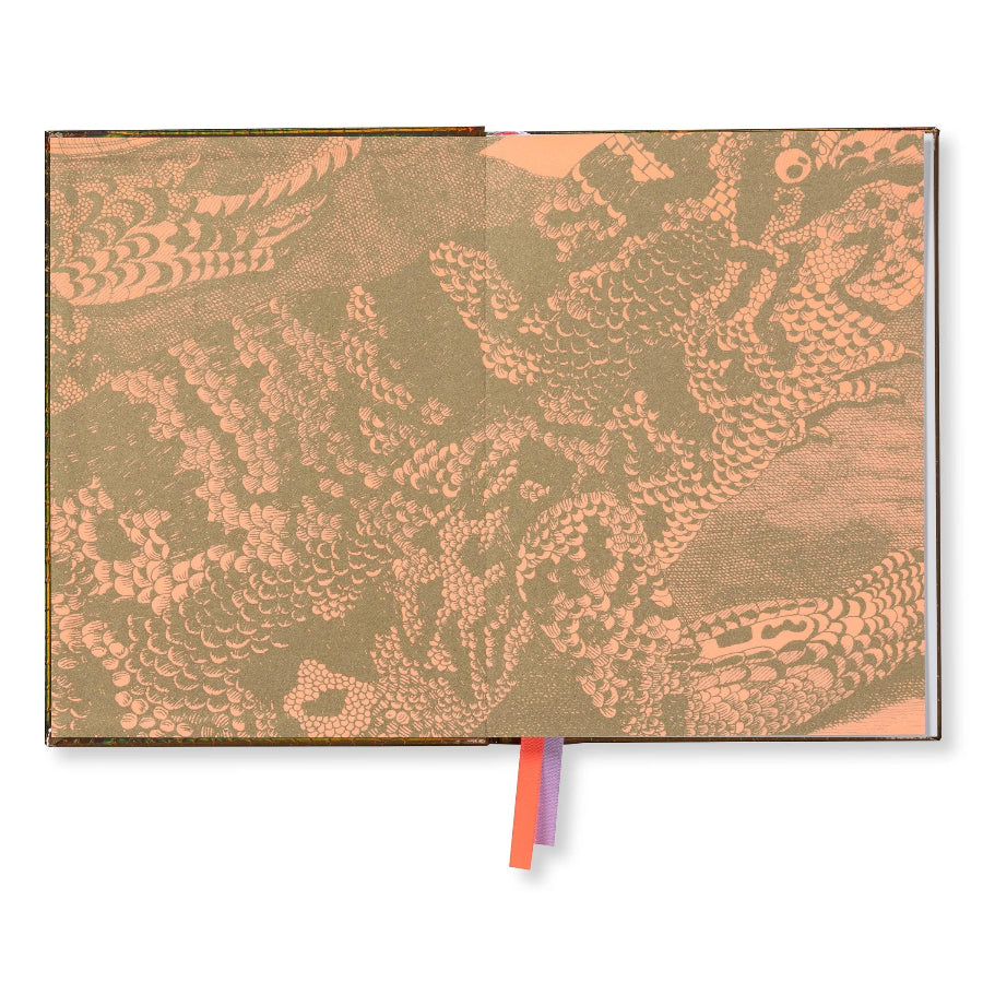 An open notebook or journal with a textured cover featuring a detailed dragon illustration in warm peach and olive tones, with two ribbon bookmarks peeking out from the bottom.